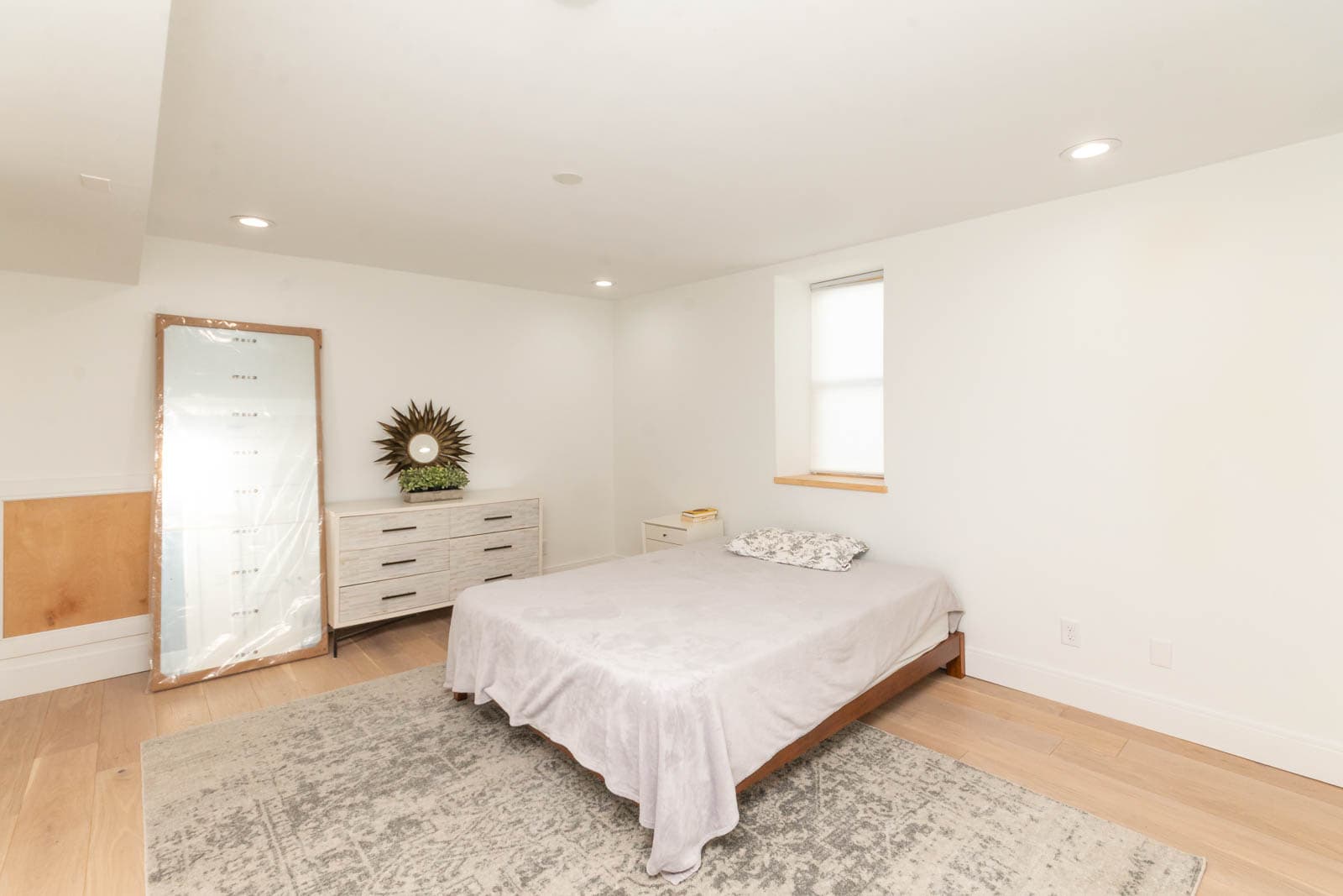 Minimalist staged bedroom with light hardwood floors